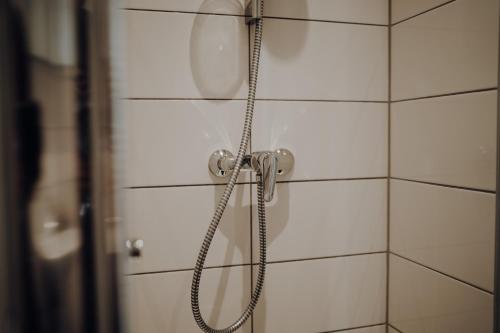a shower with a hose attached to a white tiled wall at Ferienwohnung Alte Wäscherei II in Kitzingen