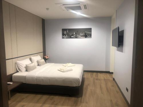 a bedroom with a bed with white sheets and a television at S.R.SUNSHINE HOTEL in Ban Sok Dua