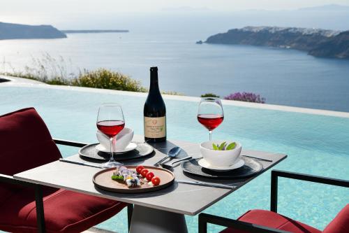 a table with two glasses of wine and a plate of food at White Pearl Cavalieri in Imerovigli