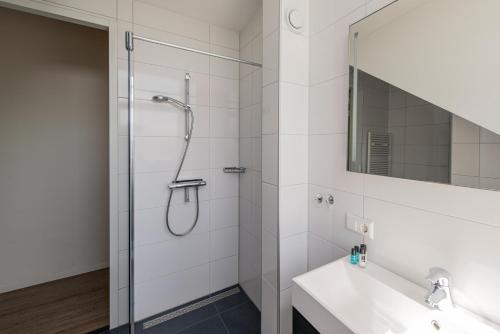 ein Bad mit einer Dusche, einem Waschbecken und einem Spiegel in der Unterkunft Woning "Villa Zoutelande" in Zoutelande