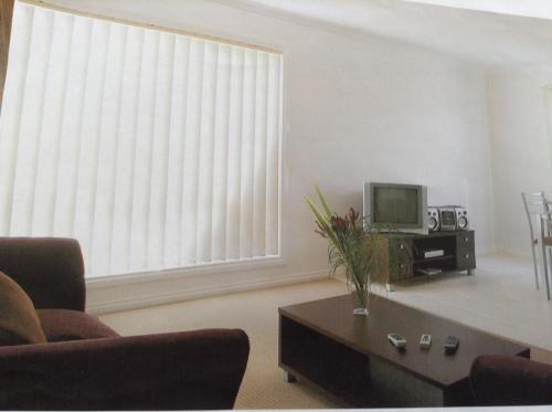 a living room with a couch and a tv at Melton Motor Inn and Apartments in Melton