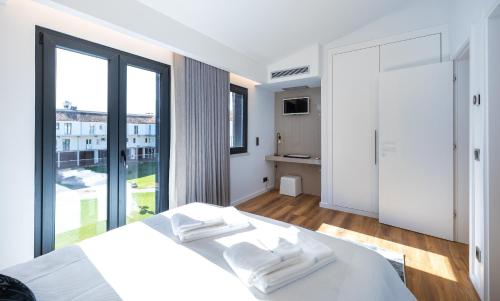 a white bedroom with a bed and a large window at Medusa Luxury Marina in Vilamoura