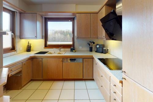 cocina con armarios de madera, fregadero y ventana en FERIENHAUS in der Natur en Wüstenrot