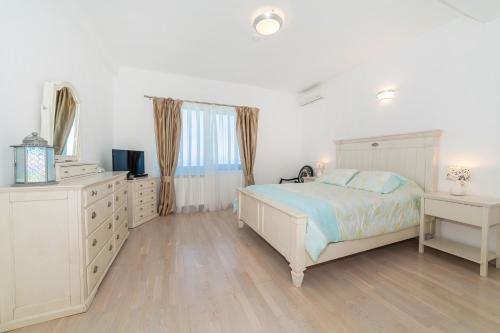 a white bedroom with a bed and a dresser at Villa Eagle Eye Montenegro in Kotor