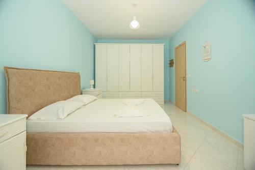 - une chambre avec un lit blanc et des murs bleus dans l'établissement DANTE APARTAMENT, à Vlorë