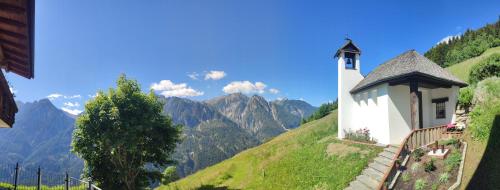 a lighthouse on a hill with mountains in the background at Appartements Obergollerhof in Assling