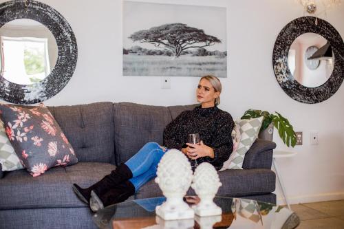 a woman sitting on a couch holding a glass at 1926 Self Catering in Piketberg