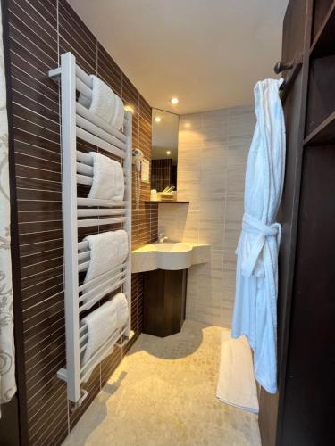 een badkamer met een wastafel en witte handdoeken bij L'Hôtel Le Cheval Noir in Moret-sur-Loing