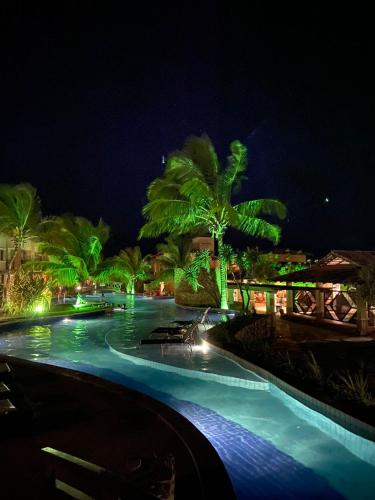 ピパにあるApartamento mobiliado no Pipa Paradiseの夜間のヤシの木と灯りのあるスイミングプール
