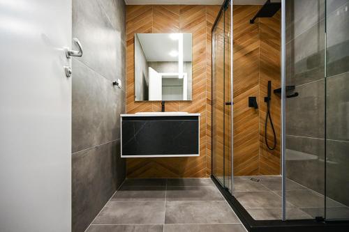 a bathroom with a shower with a sink and a mirror at Designer 2-BD Apartment with Parking near Center of Varna in Varna City