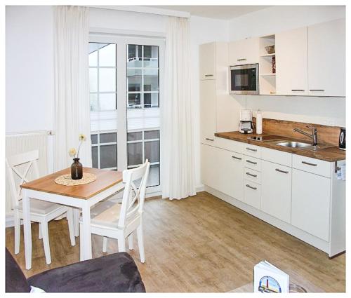 una cucina con tavolo in legno e una cucina con armadietti bianchi di Haus Götting Wohnung 2 a Norderney