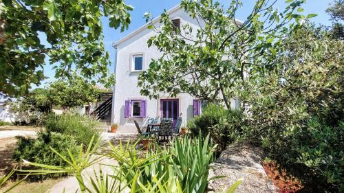 a white house with purple doors and trees at Casa di Castello in Mali Lošinj