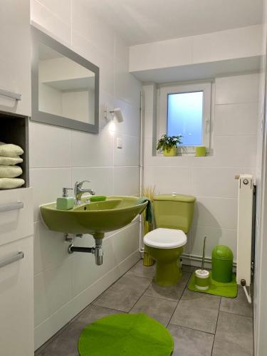 a bathroom with a green sink and a toilet at La cave du Pi'Style in Ingwiller