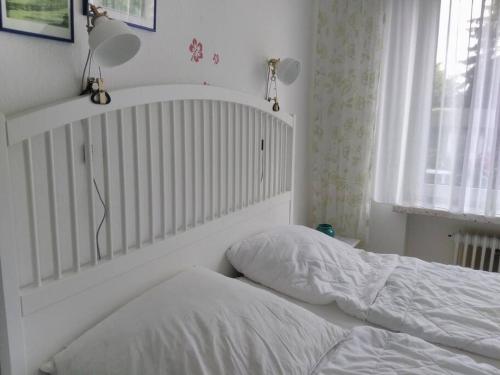 1 dormitorio con 1 cama con sábanas blancas y ventana en Ferienwohnung Finn im Haus Maarten en Cuxhaven
