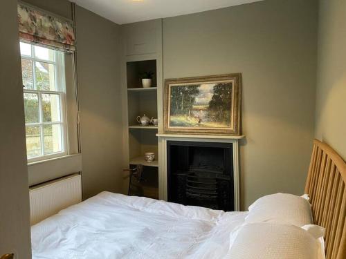 a bedroom with a bed and a fireplace with a painting at Regency cottage 10 minutes from Bath city centre in Bath