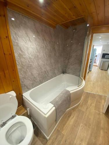 a bathroom with a toilet and a bath tub and a toilet sidx sidx at Relaxing costal retreat sleeps four people in Hastings