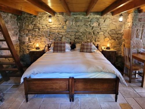 a bedroom with a large bed in a stone wall at Loch Lomond shore Boat House in Balmaha