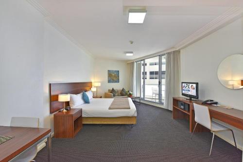 ein Hotelzimmer mit einem Bett und einem Schreibtisch in der Unterkunft APX World Square in Sydney