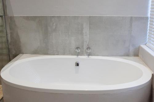 a white bath tub in a bathroom next to a window at 1926 Self Catering in Piketberg