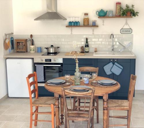 cocina con mesa de madera con sillas y nevera en Le Manoir de la Beslière - Gîte et Chambres d'hôtes, en Folligny