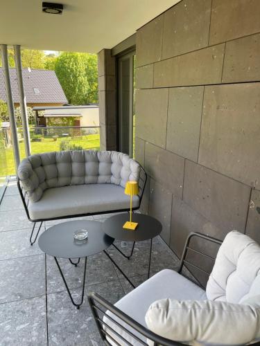 a patio with a couch and two chairs and a table at Basalt Lodge am Lehnitzsee in Oranienburg
