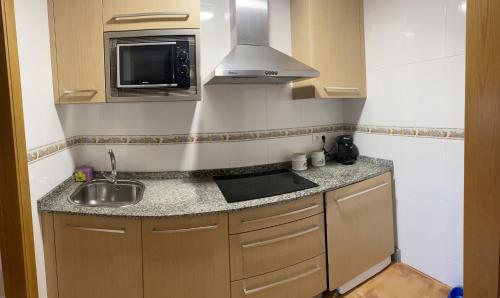 eine kleine Küche mit einer Spüle und einer Mikrowelle in der Unterkunft PISO DAPONTE in O Grove
