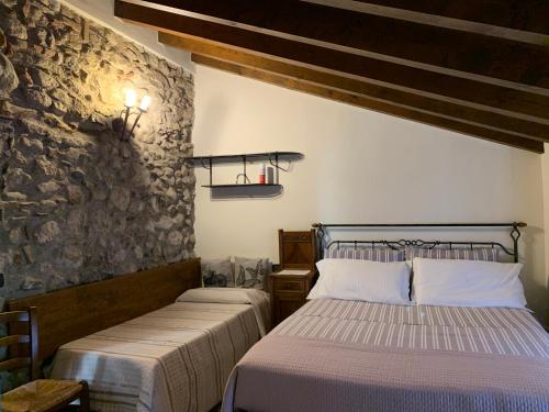 um quarto com 2 camas e uma parede de pedra em Rustico di Benellini Angela em Polpenazze del Garda