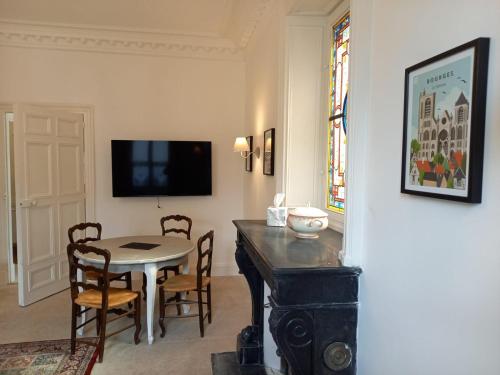- une salle à manger avec une table, des chaises et une télévision dans l'établissement Clos Montcenoux, au coeur de Bourges., à Bourges