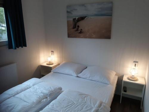 two beds in a room with two lamps on tables at Camping de Duinhoeve Chalet Schelp not for companies in Nieuw-Haamstede