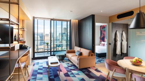 a living room with a couch and a room with a view at Hotel Indigo Adelaide Markets by IHG in Adelaide