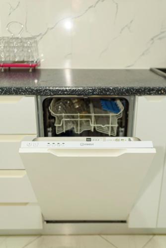 a cat sitting on top of an oven under a counter at DANTE APARTAMENT in Vlorë