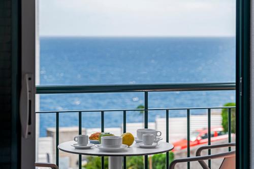 a table with cups and pastries on a balcony at Reis Magos IV by An Island Apart in Caniço