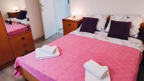 a bedroom with a pink bed with towels on it at Apartment Bitinada in Rovinj