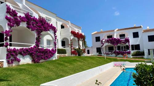 a building with purple flowers and a swimming pool at Playa Parc Apartments in Son Parc