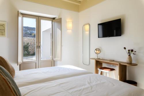 a white bedroom with a bed and a window at Camarades Mykonos in Ano Mera