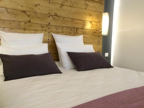 ボルドーにあるStudio cosy centre historique Saint-Michelの白い枕2つと木製の壁が備わるベッドルーム1室
