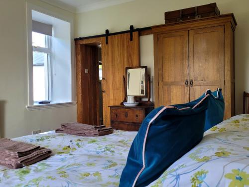 a bedroom with a bed with a dresser and a tv at Blair Cottage in Rowardennan