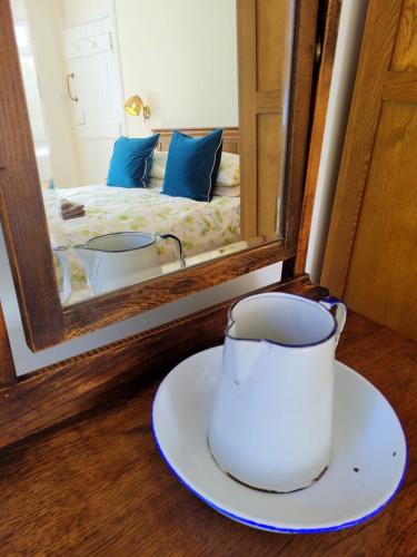a cup on a plate in front of a mirror at Blair Cottage in Rowardennan
