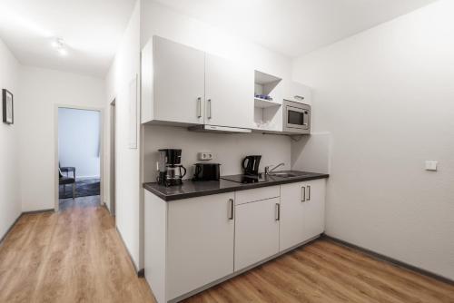 a kitchen with white cabinets and a wooden floor at Familienapartment nahe der Frauenkirche in Dresden