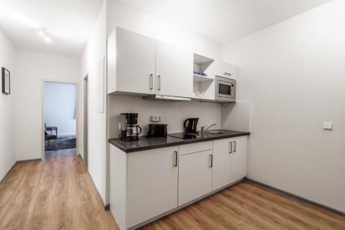 una cucina con armadietti bianchi e pavimenti in legno di Familienapartment nahe der Frauenkirche a Dresda