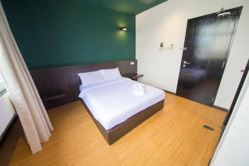 a bedroom with a white bed with a green wall at Room V Jalan Jenang by SECOMS in Batu Pahat