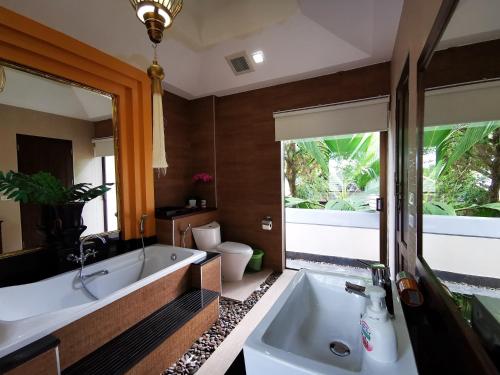 a bathroom with a tub and a large mirror at YiZen Boutique Phutara 5 Bedroom Villa in Nong Prue
