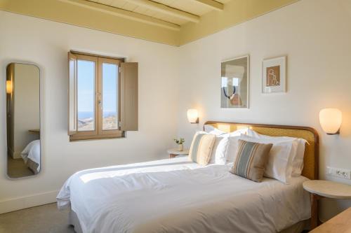 a bedroom with a large white bed and a window at Camarades Mykonos in Ano Mera
