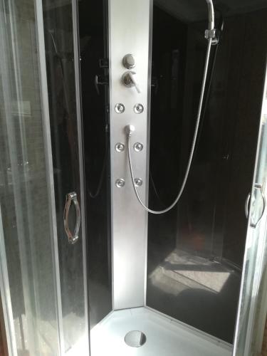 a shower stall with a glass door with a shower at Saltlake apartman in Siófok