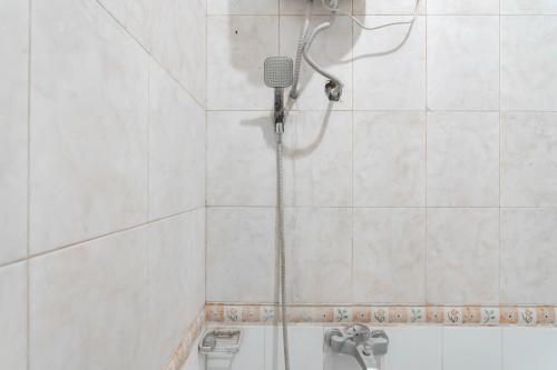 a shower in a white tiled bathroom at RedDoorz Plus At Hotel Sofia Pangandaran in Pangandaran