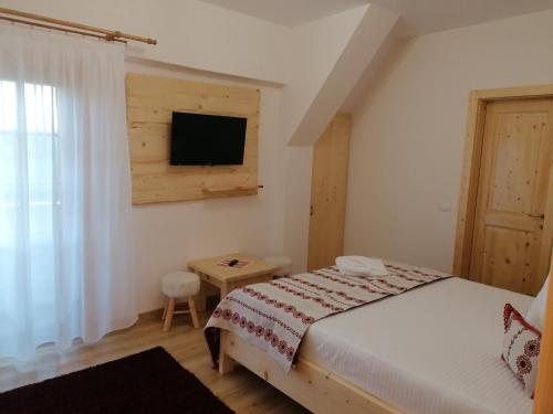 a bedroom with a bed and a tv on the wall at Pensiunea Căsuța din Deal in Moisei