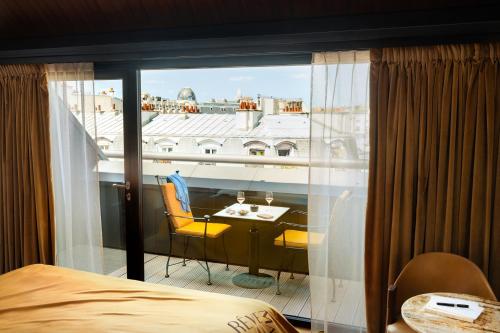 a room with a balcony with a table and chairs at Hôtel Madame Rêve in Paris