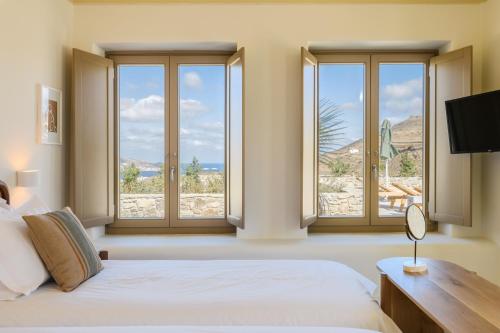 a bedroom with windows and a bed and a television at Camarades Mykonos in Ano Mera