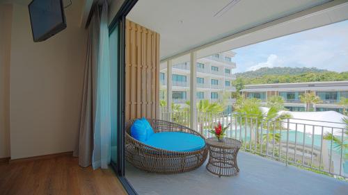 a balcony with a wicker chair and a large window at Infinity Aonang Krabi in Ao Nang Beach