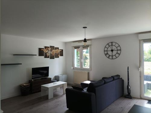 un salon avec un canapé et une horloge au mur dans l'établissement Maison de vacance mi ville, mi campagne, à Boé